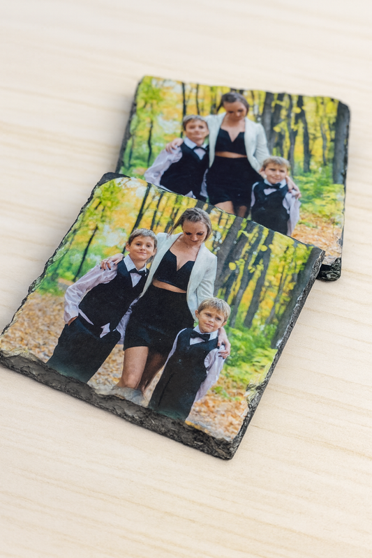 Two slate coasters with a family photo printed on them, placed on a wooden surface.