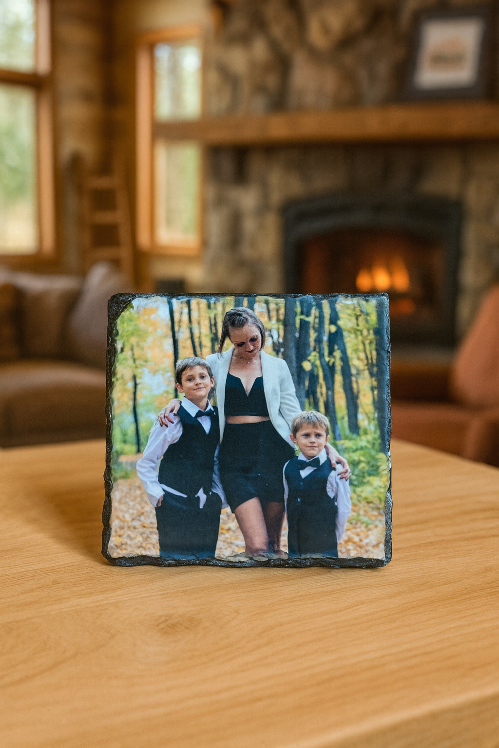 Slate photo plaque with a family in a forest setting on a wooden surface.